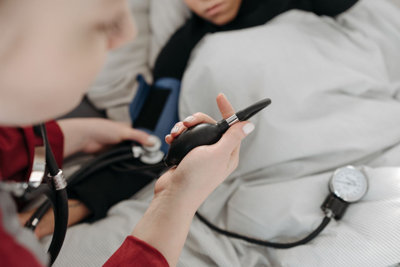 A healthcare professional uses a sphygmomanometer to check a patient's blood pressure at home.
